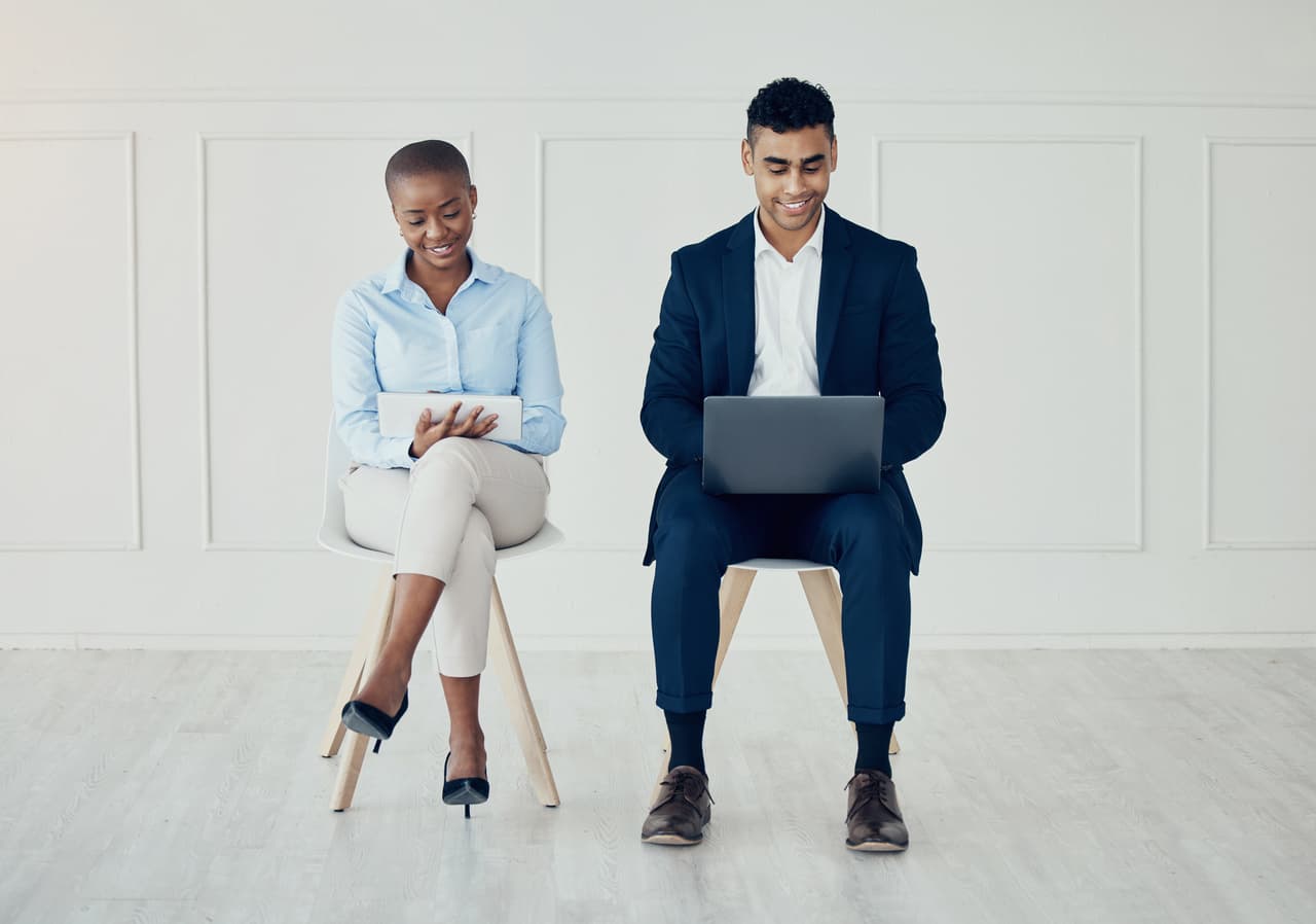 a business woman and man sitting and dealing with their digital devices to test