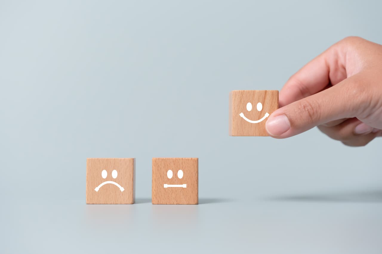 a hand picking a smiley face from wooden blocks