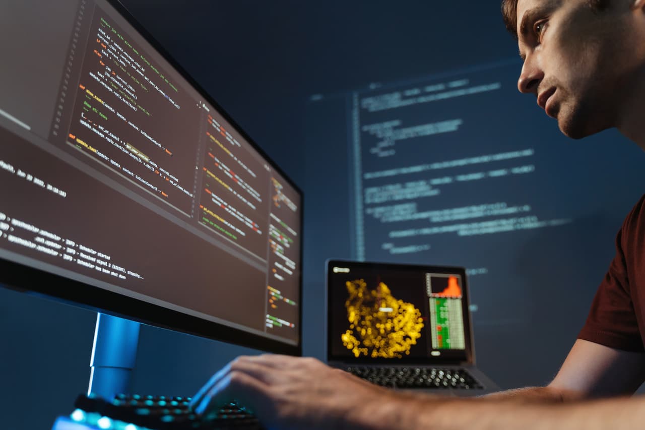 a man who is a programmer working on different computers to integrate chatbot
