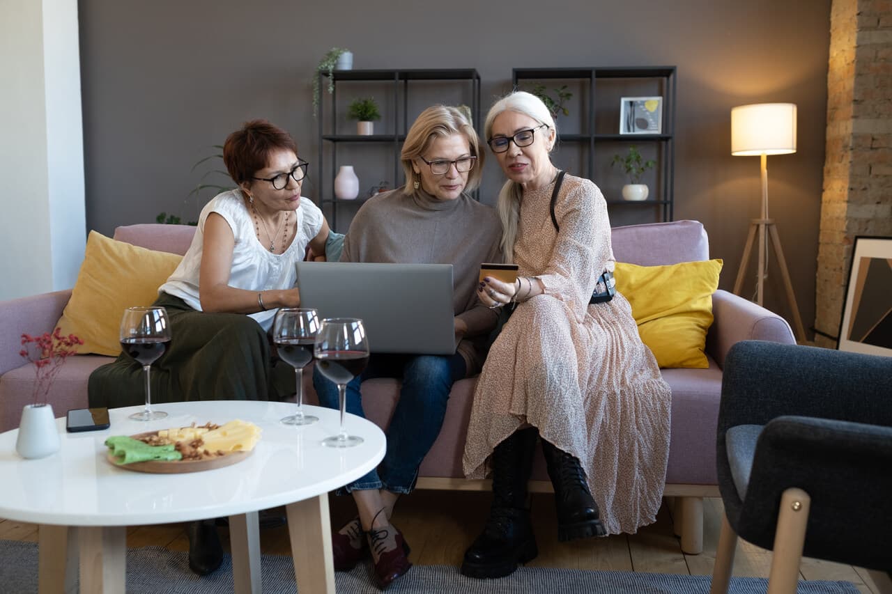 three women sitting on a couch shopping online