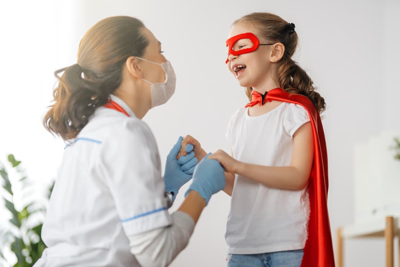 pediatrician conversing with in superhero costume child patient