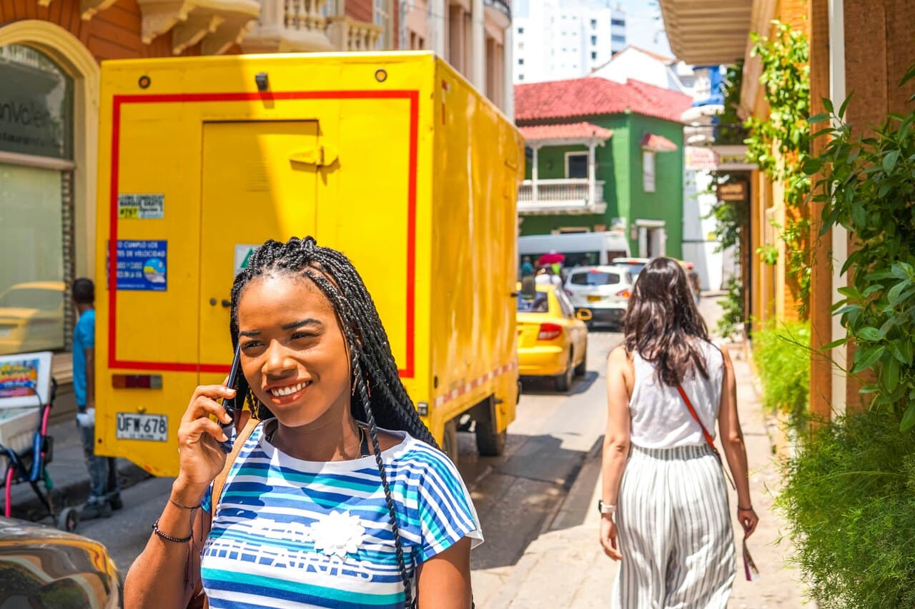 a woman talking on the phone and there is traffic behind her