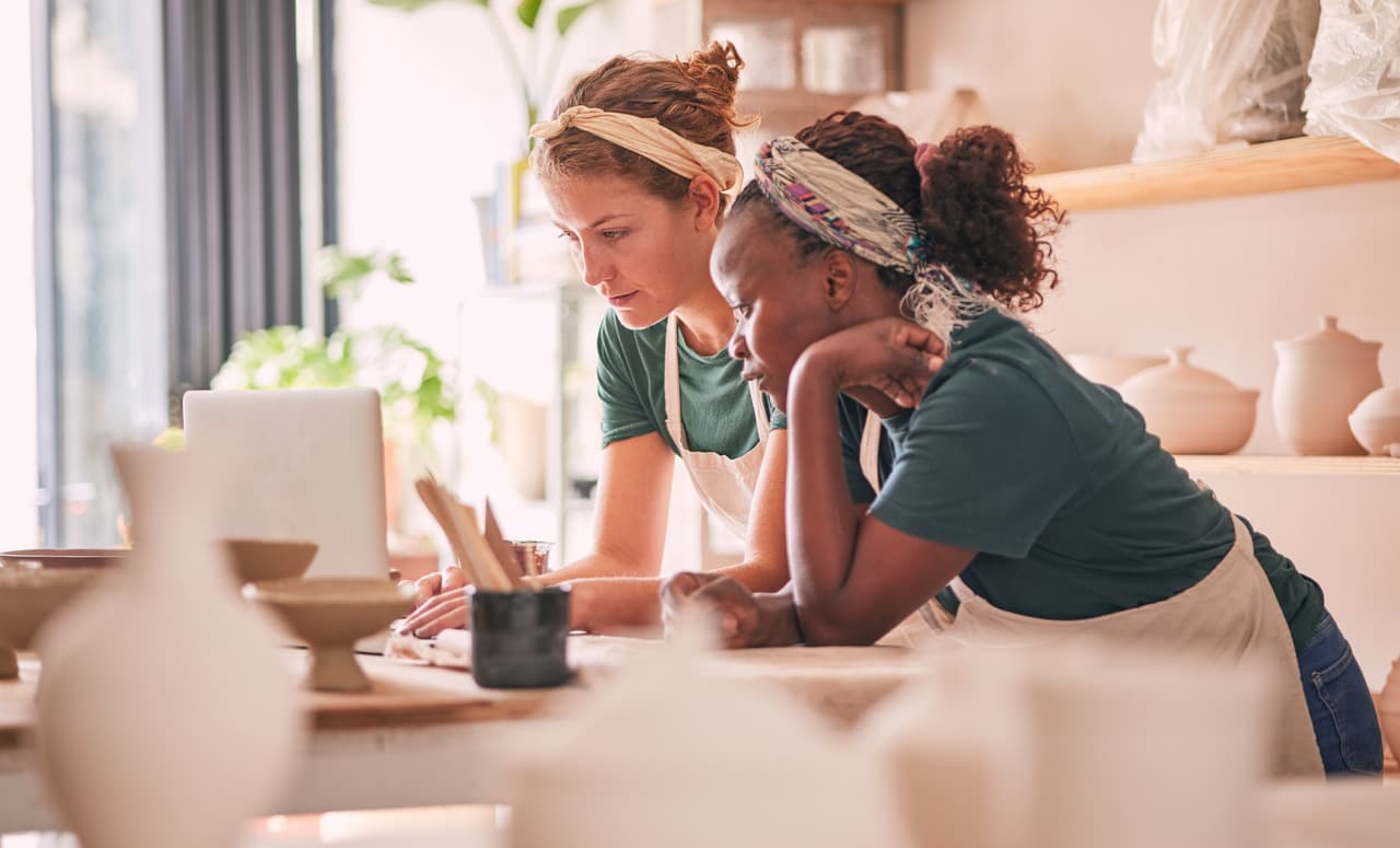 two women whose profession is ceramic and pottery dealing with a laptop for ecommerce