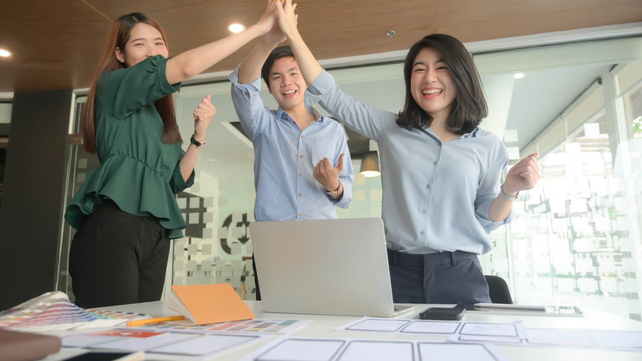 team cheering and raising their hands for success