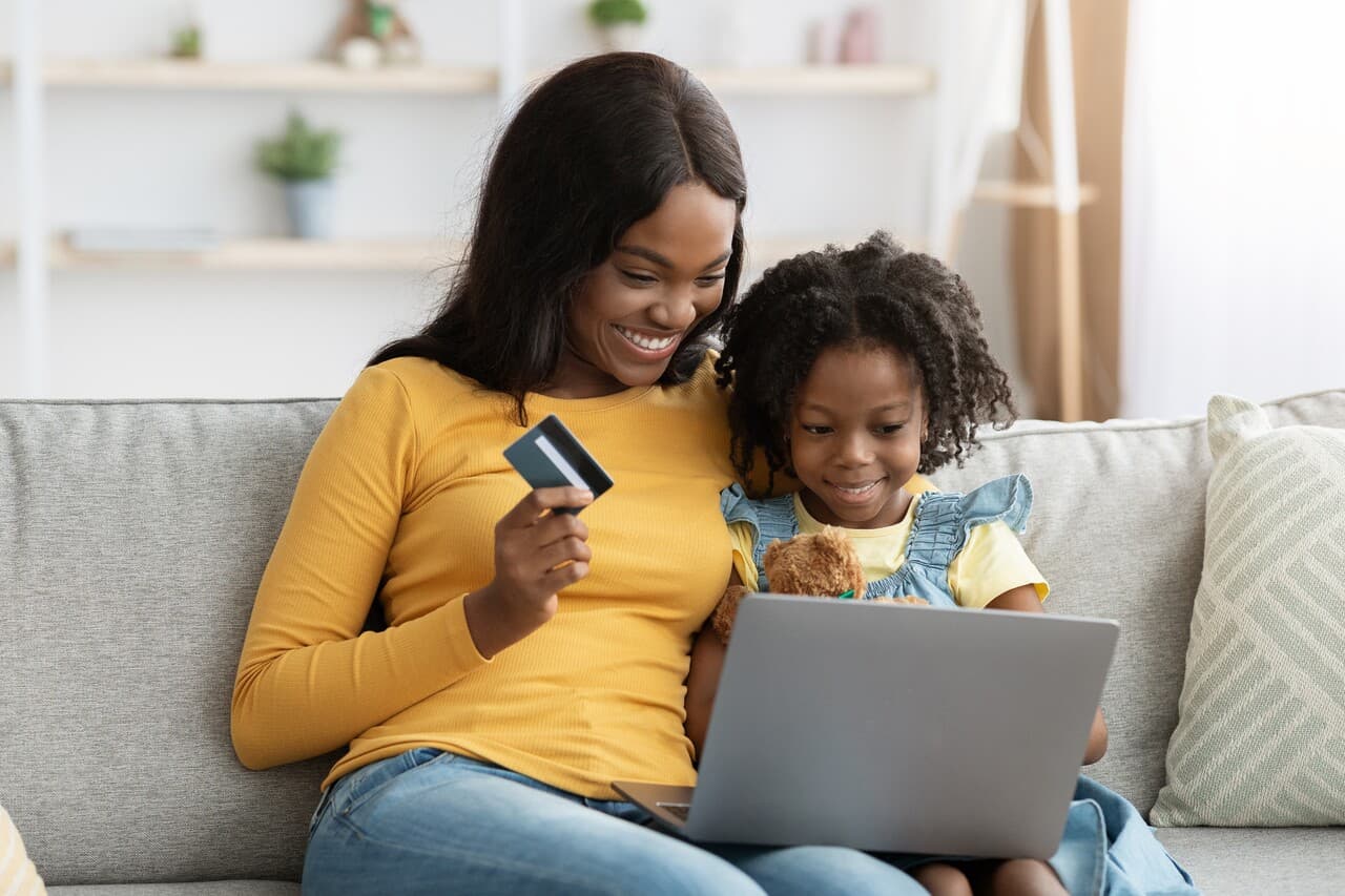 a mother and a daughter wearing yellow sitting on a couch shopping online