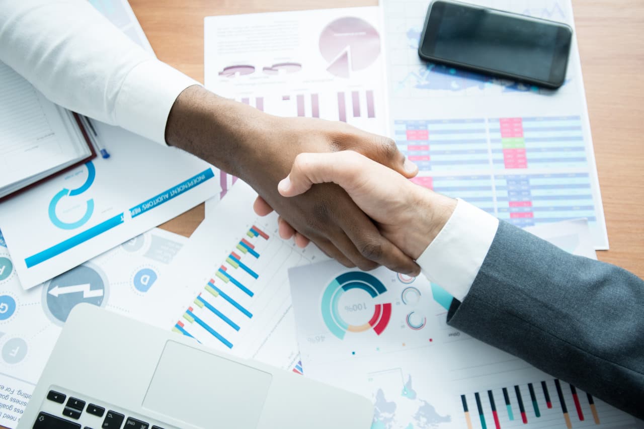 two men shaking their hands over the reports and analytics