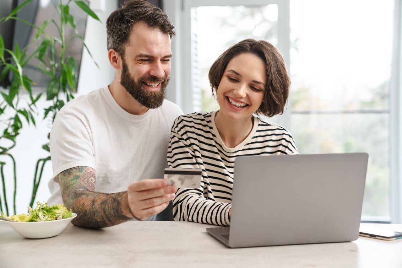 a couple smiling and doing online shopping in their house