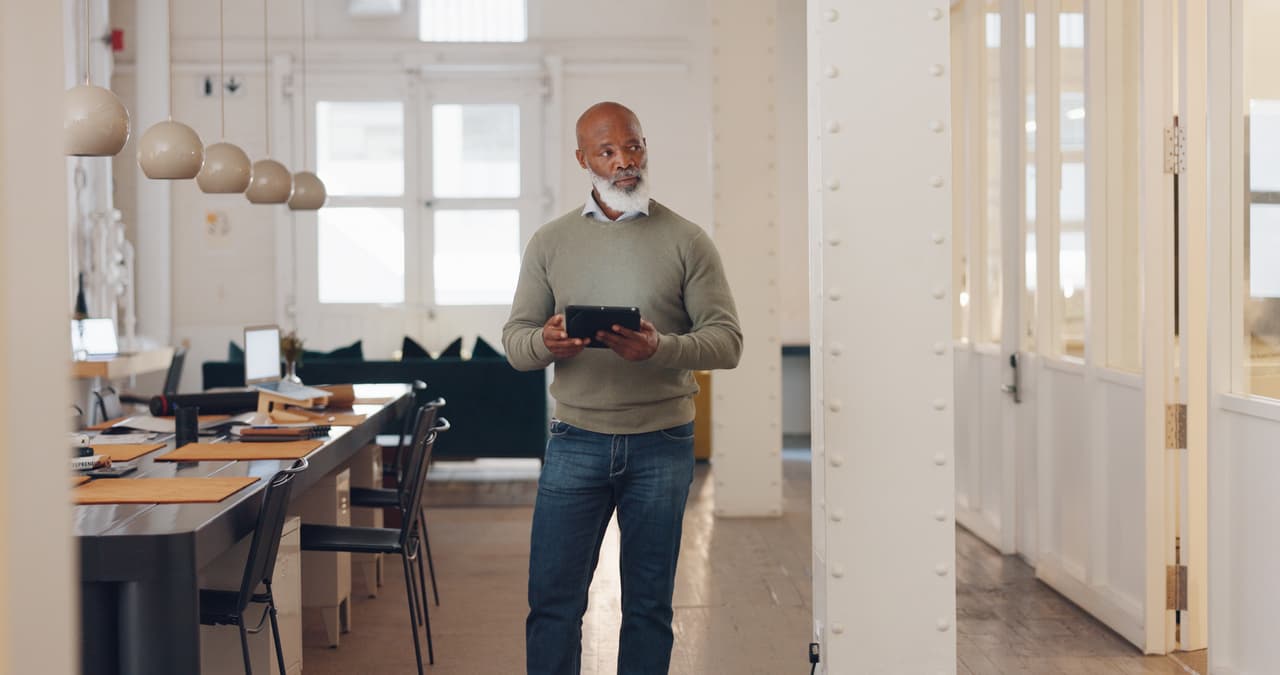 A real estate agent man in an office holding a tablet, appearing focused and engaged in his work.