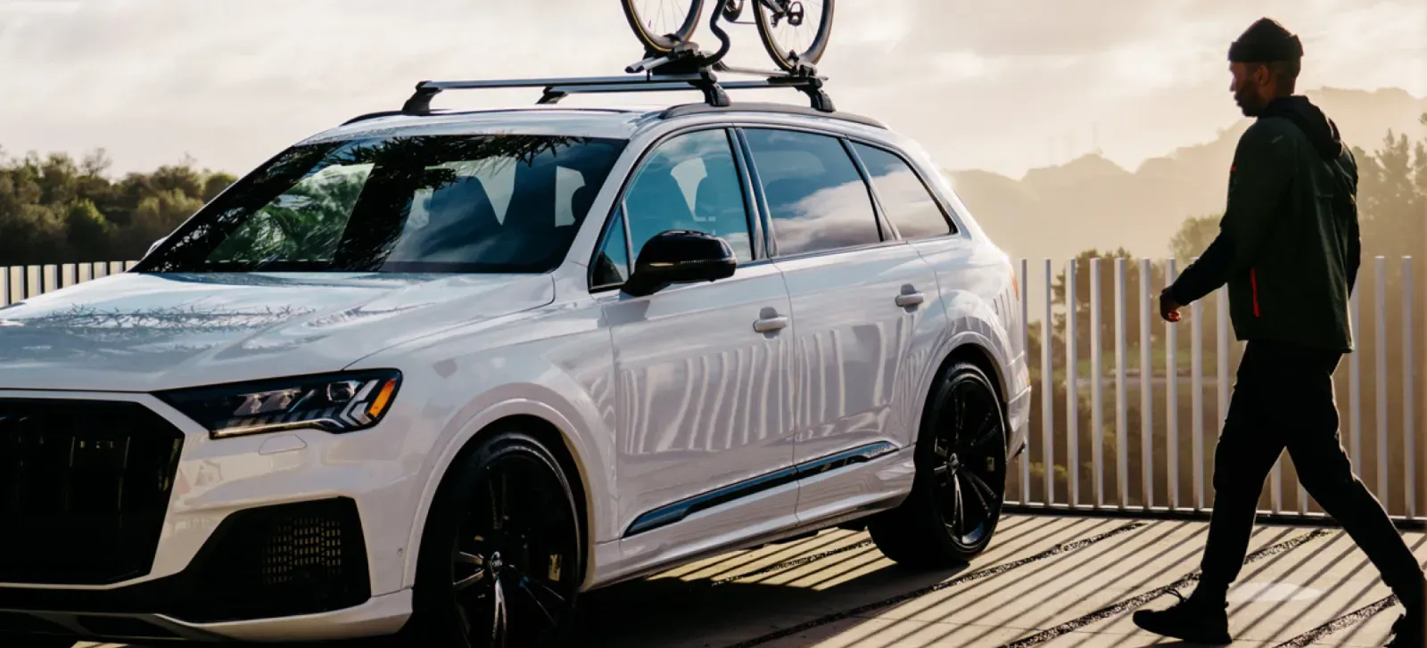 White SUV with a bicycle on its roof and a person walking nearby